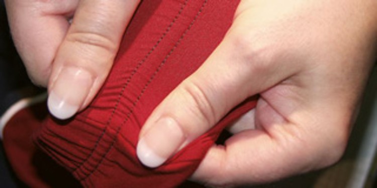 Red fabric that is being pulled alongside the seam