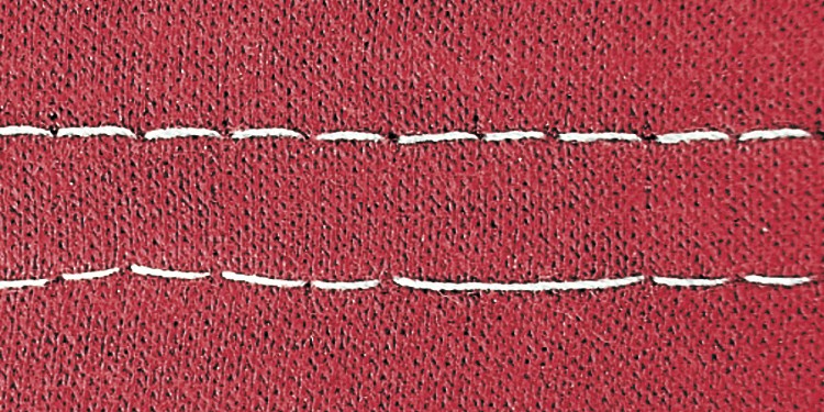 Großaufnahme eines roten Textils, auf dem Fehlstiche zu erkennen sind