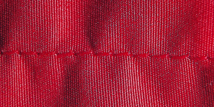close-up of a red fabric showing seam puckering